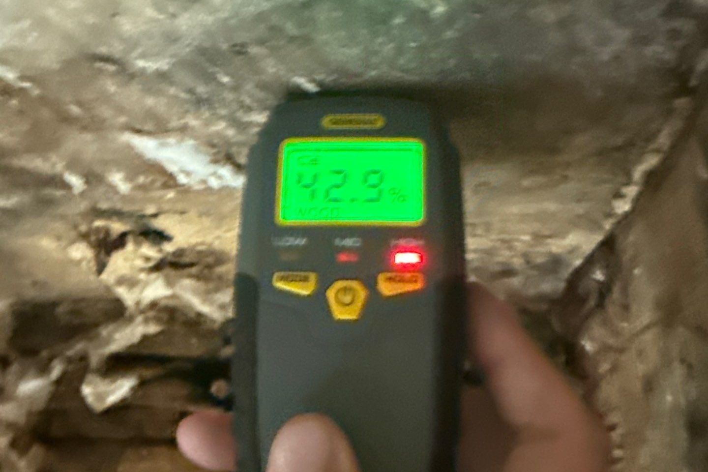 Moisture meter reading 42.9 percent on water-damaged material inside a wall during a restoration inspection